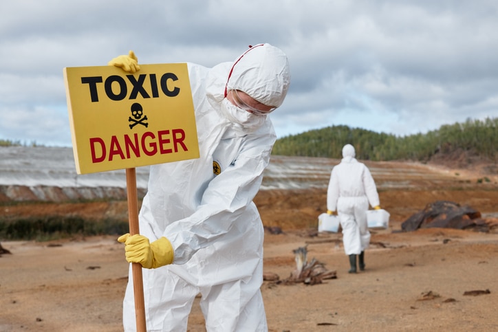 Professionals wearing HAZMAT equipement placing toxic warning sign as a result of long term biohazard contamination.